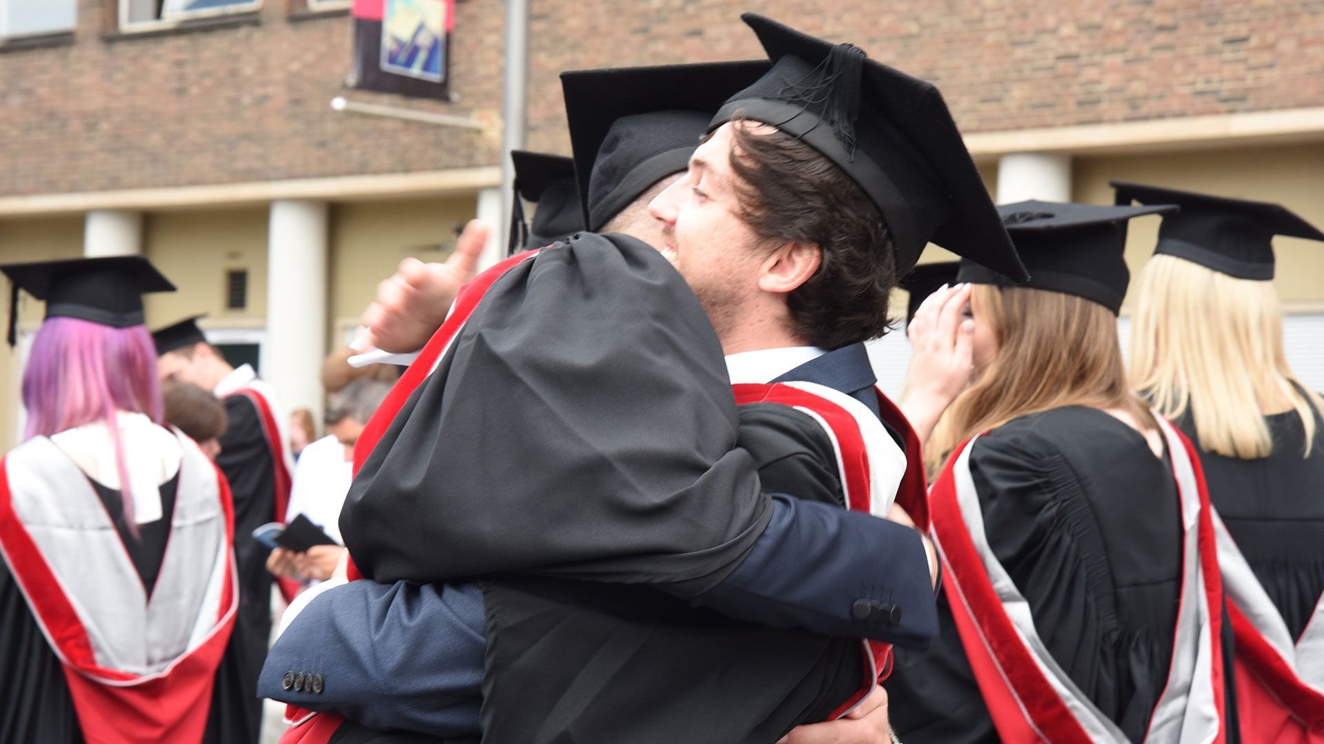 two students hugging in graduation robes