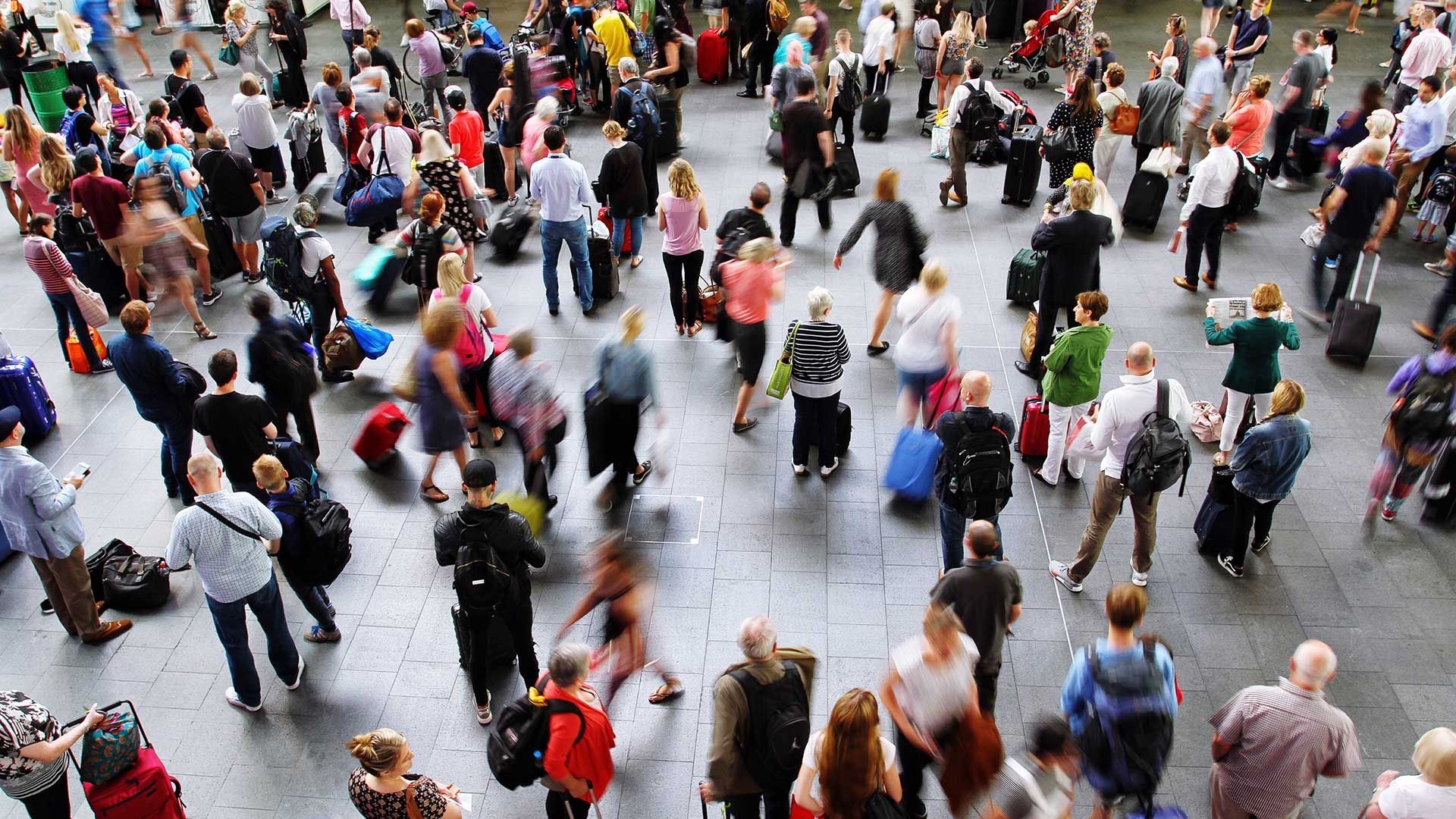 People at airport with luggage walking round and looking up 