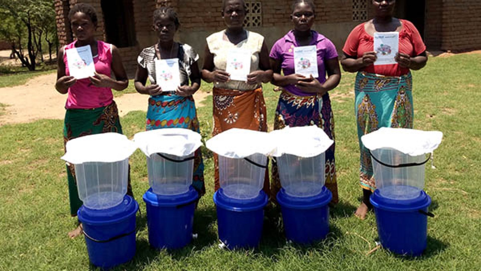 Five people stood in front of buckets ready to collect clean drinking water