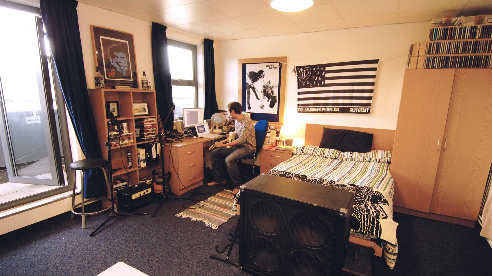 BNU student in Hughenden accommodation studio bedroom sitting at desk with musical equipment around