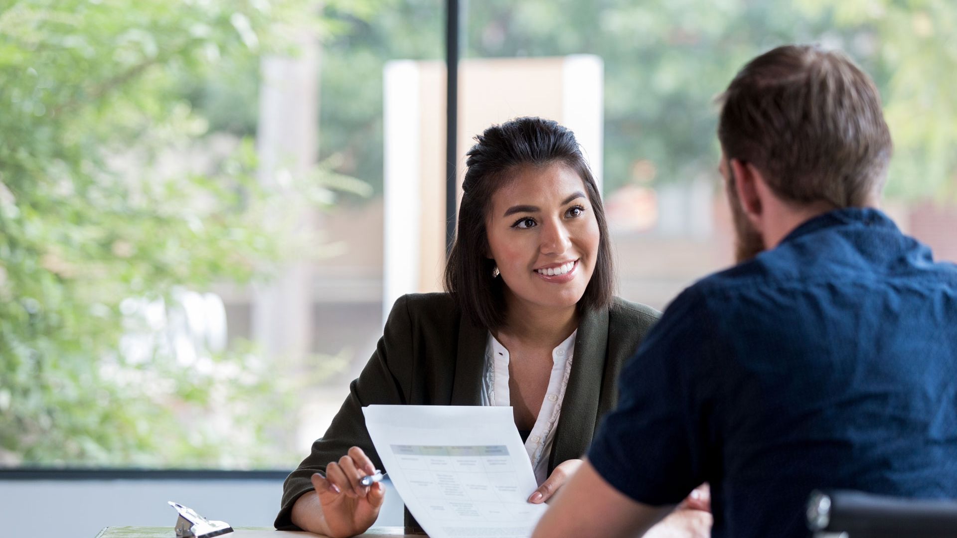 two adults together looking at documents next to a window