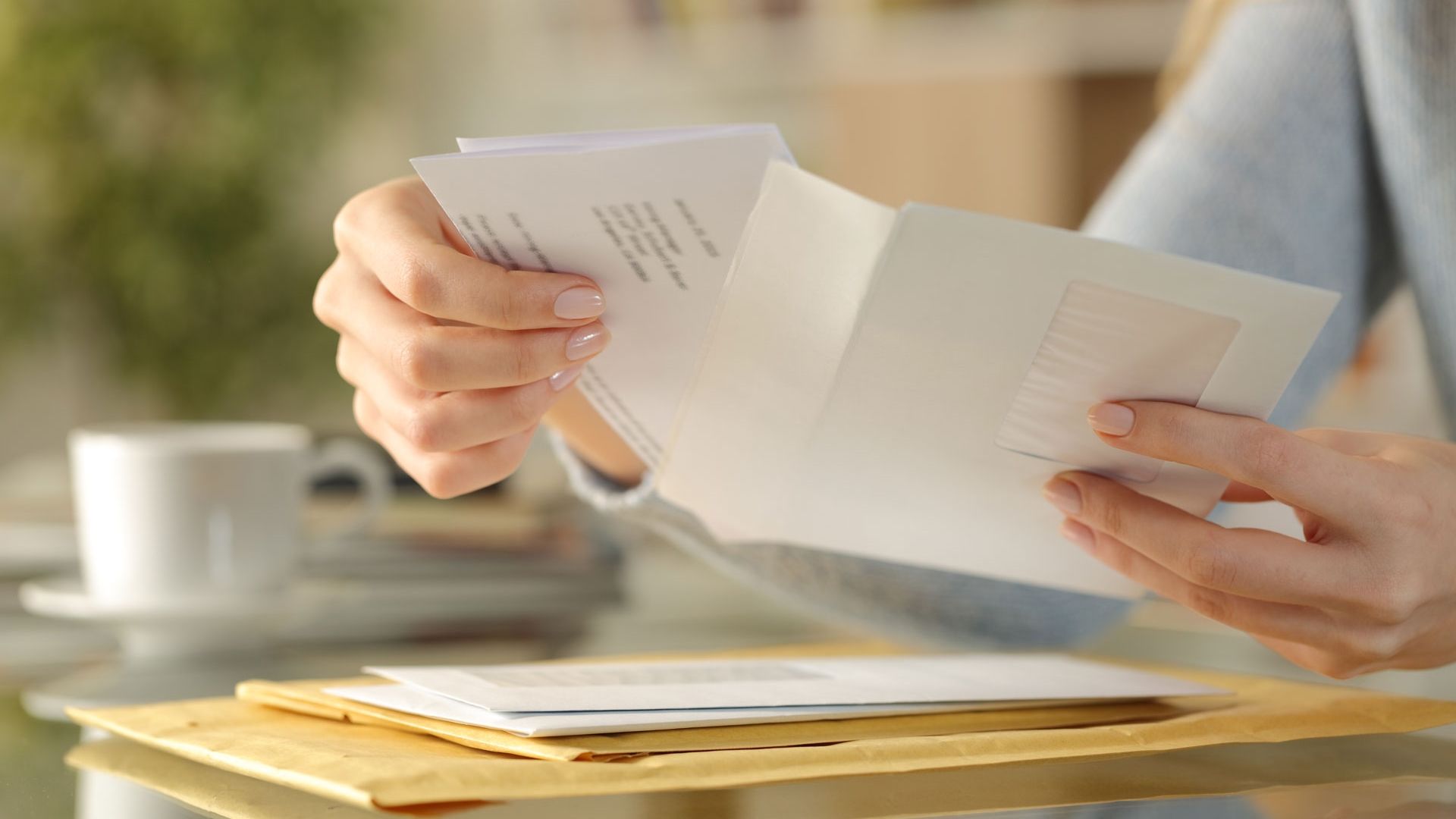 female putting letter in envelope ready to send
