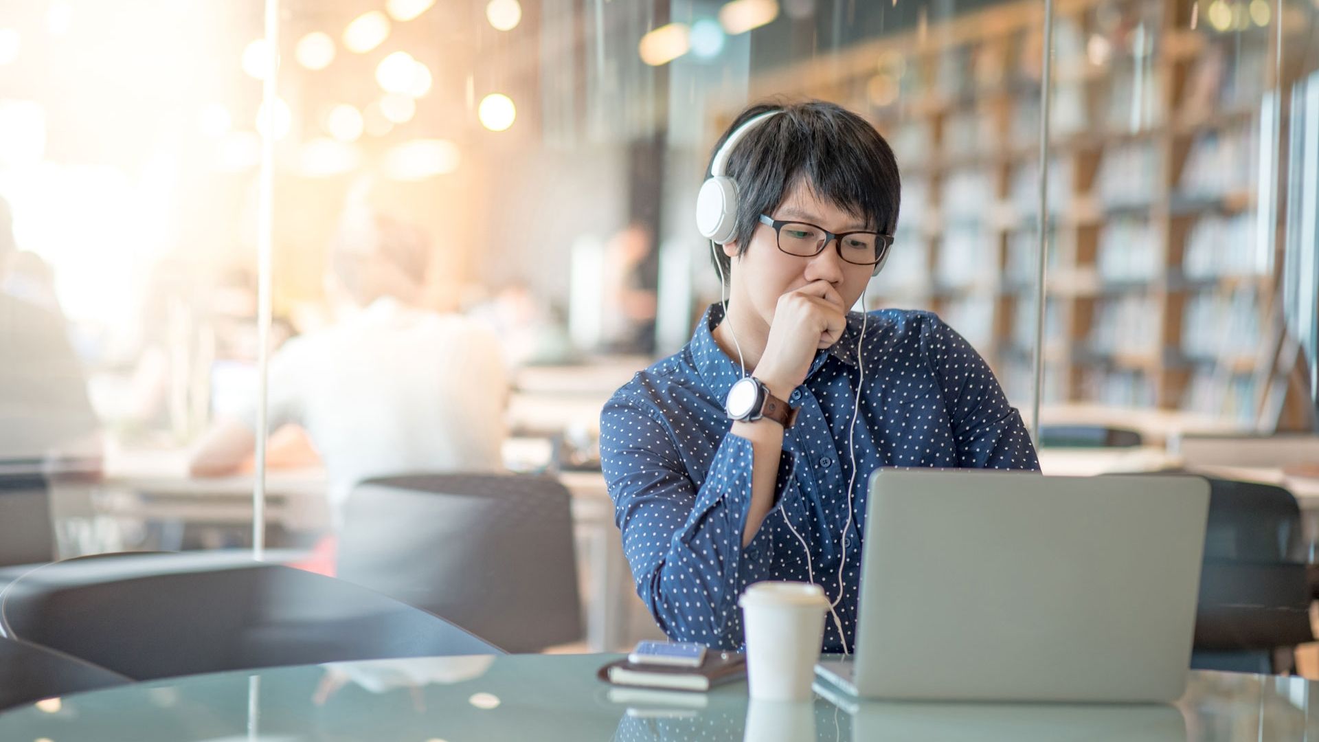 Male student in study room in library with headphones on