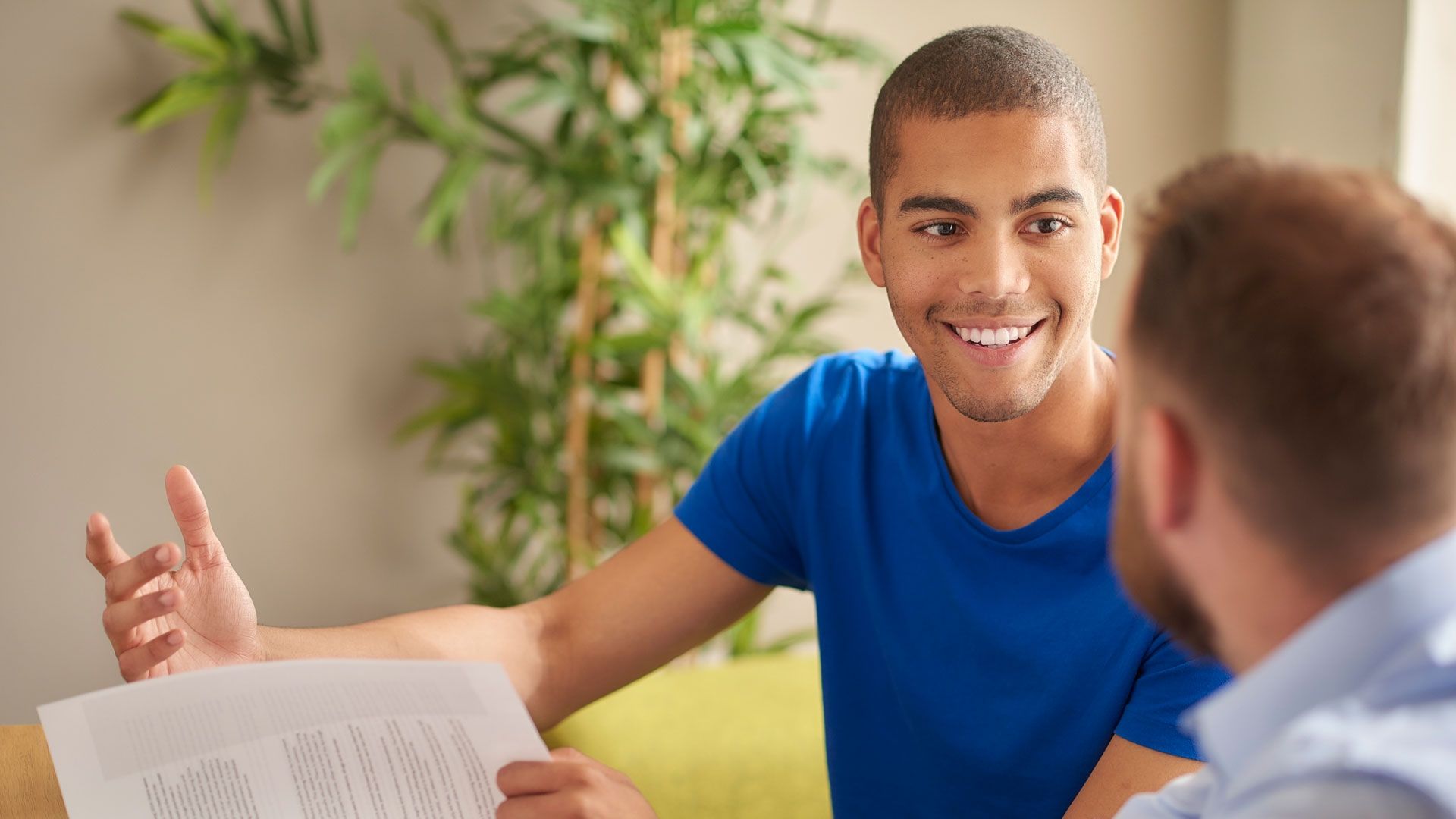 Male student sitting with lecture getting help with work