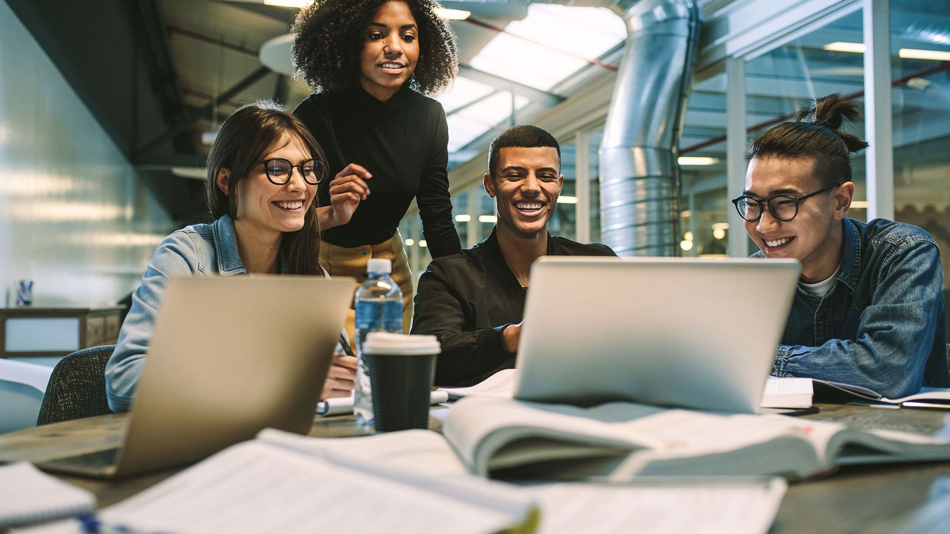 Students together at a table looking at a laptop doing group work