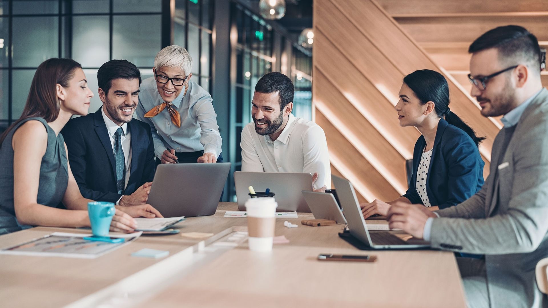 Group of adults in business meeting looking at laptops 