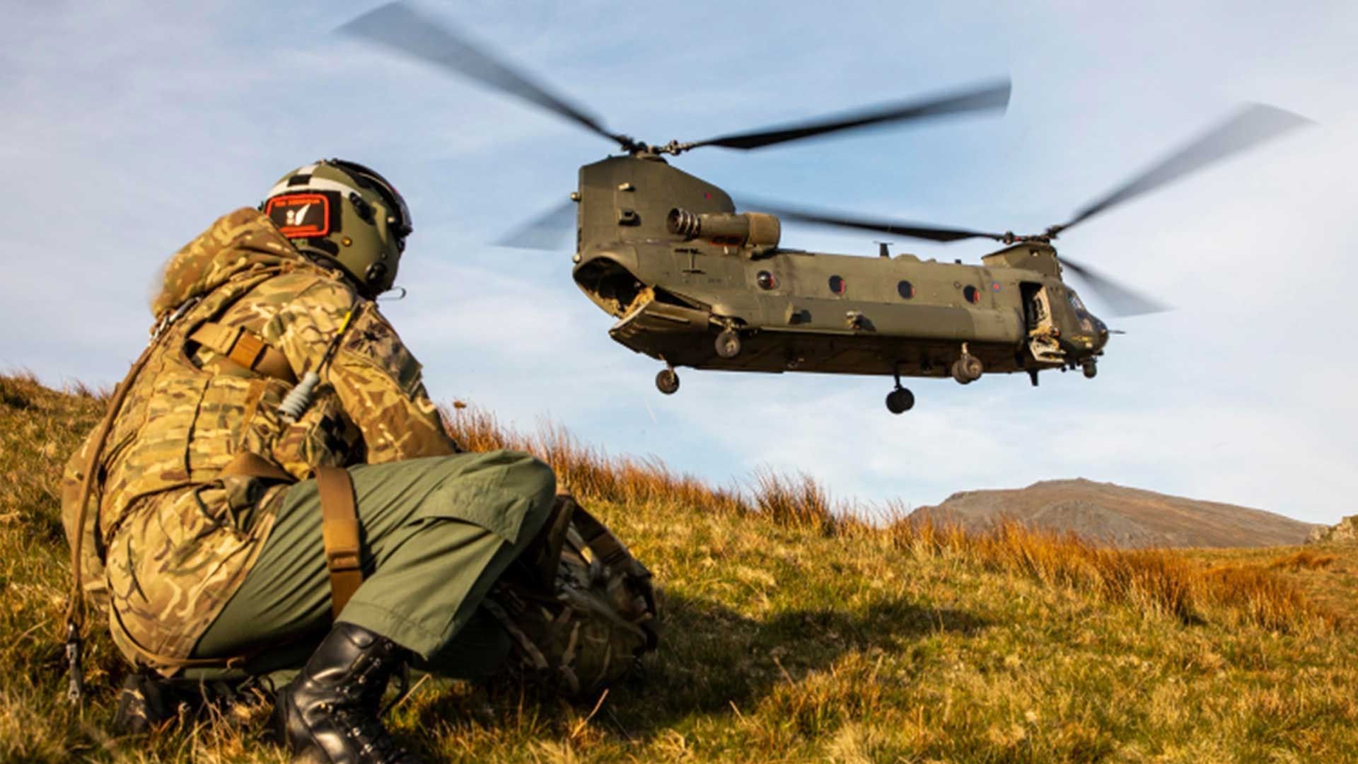 Military person in camouflage and a Chinook taking off
