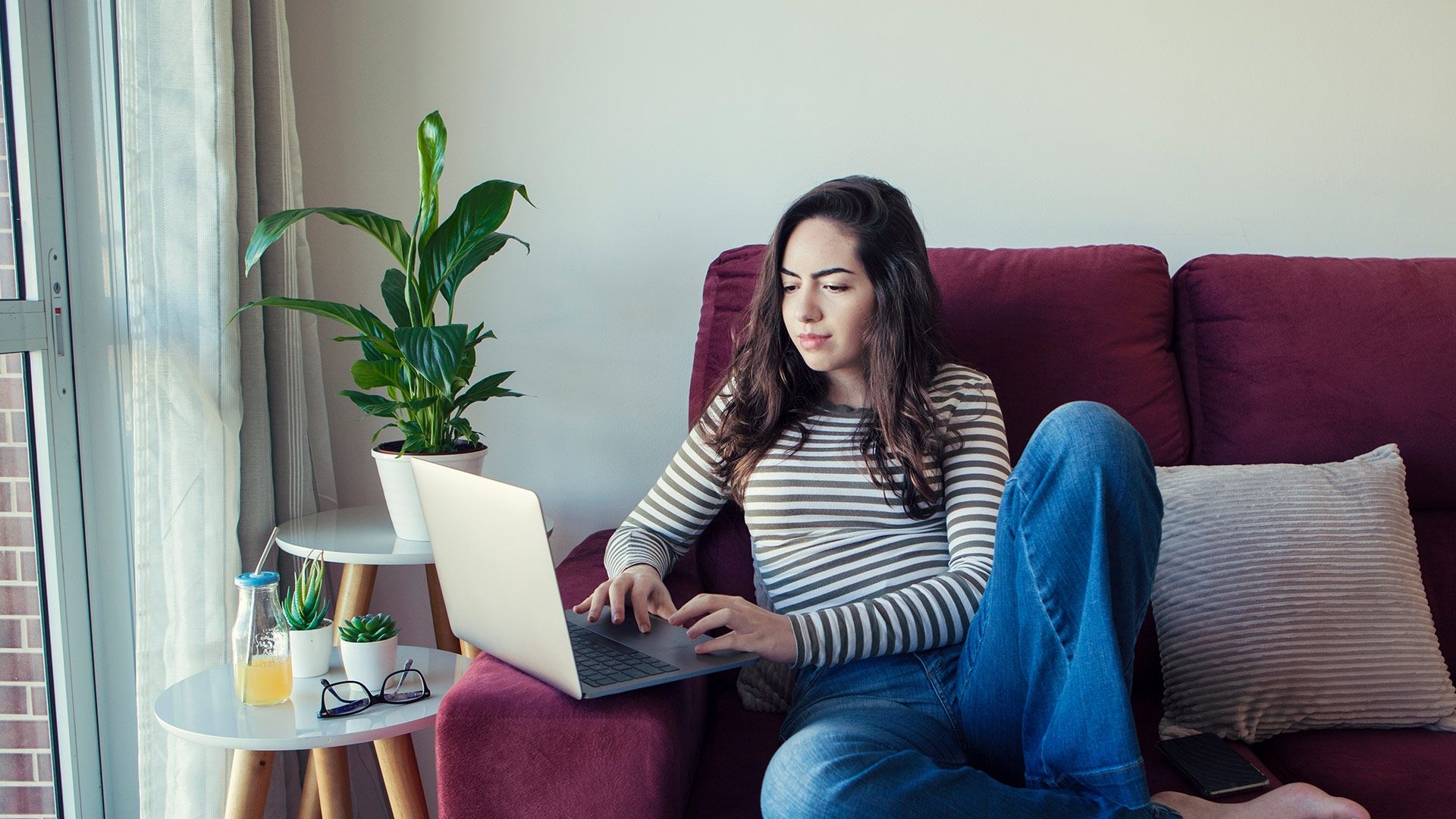 student sat on a sofa using a laptop