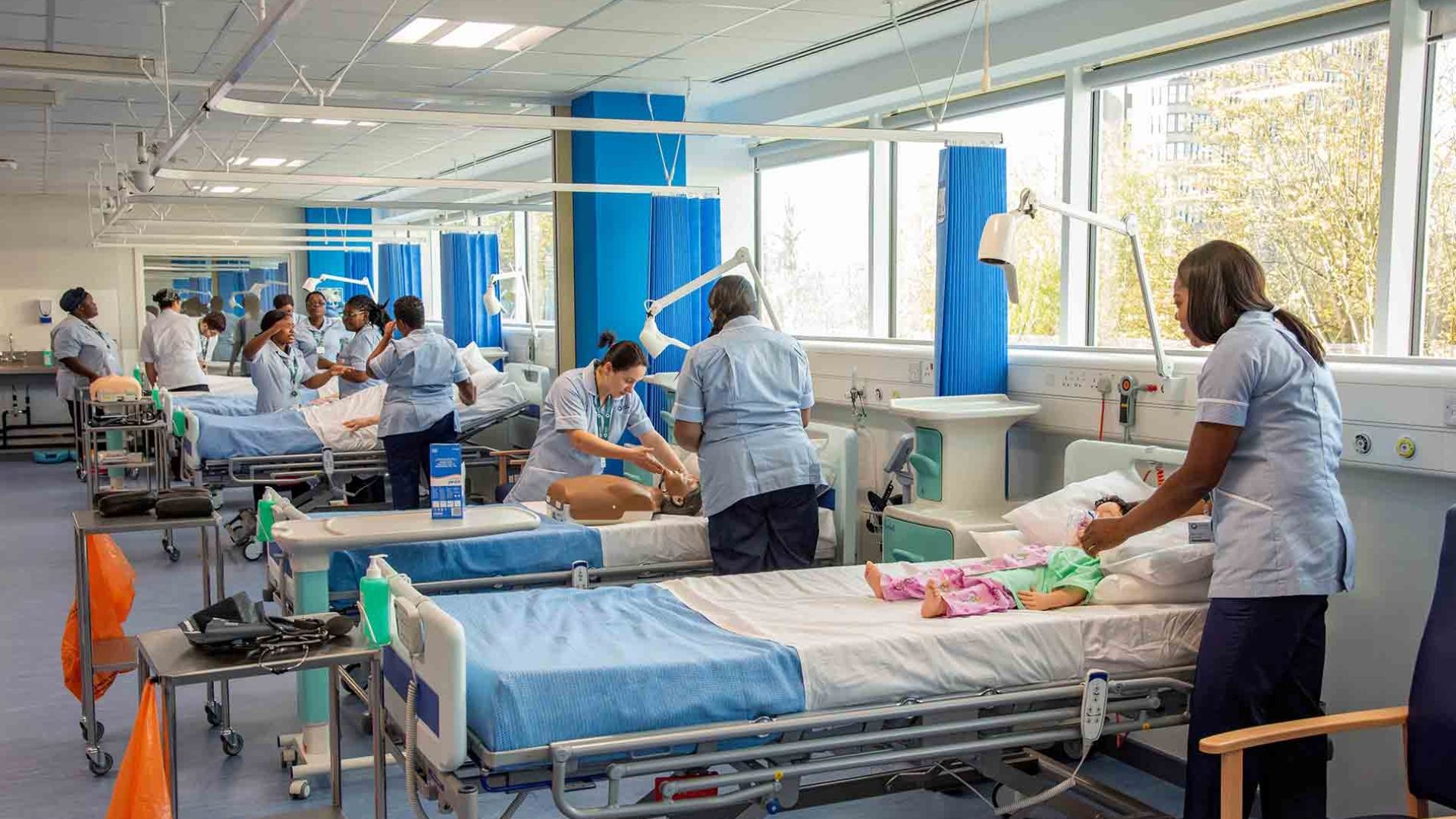 Nursing students in a hospital simulate suite attending to dummies