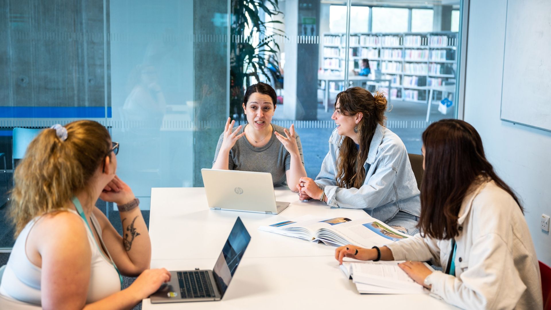 Lecturer and students talking at a table in one of the study rooms in the Library