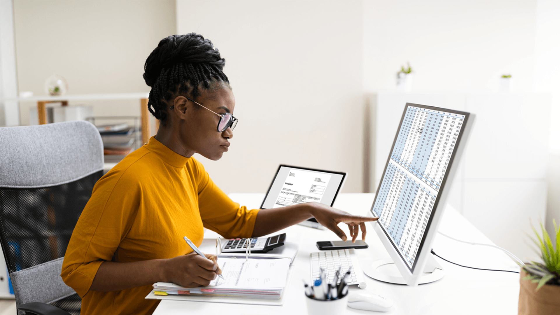 A woman sat at a desk pointing at her computer screen