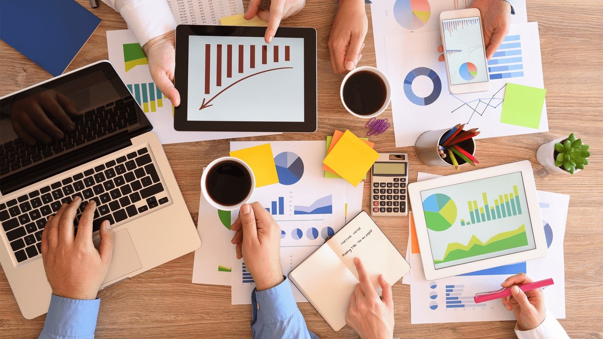 Data presented on bits of paper on a table with 3 people assessing the data in a business meeting