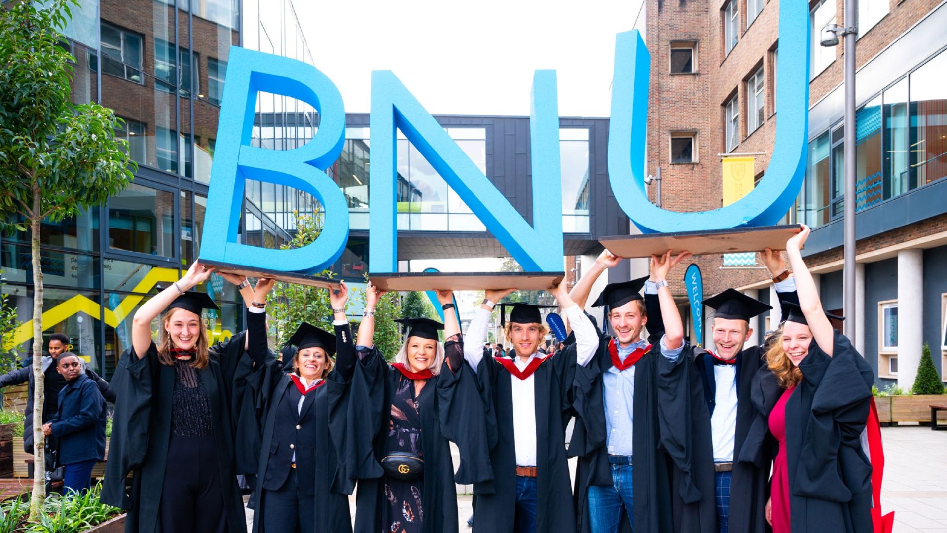 Group of graduands holding BNU sign