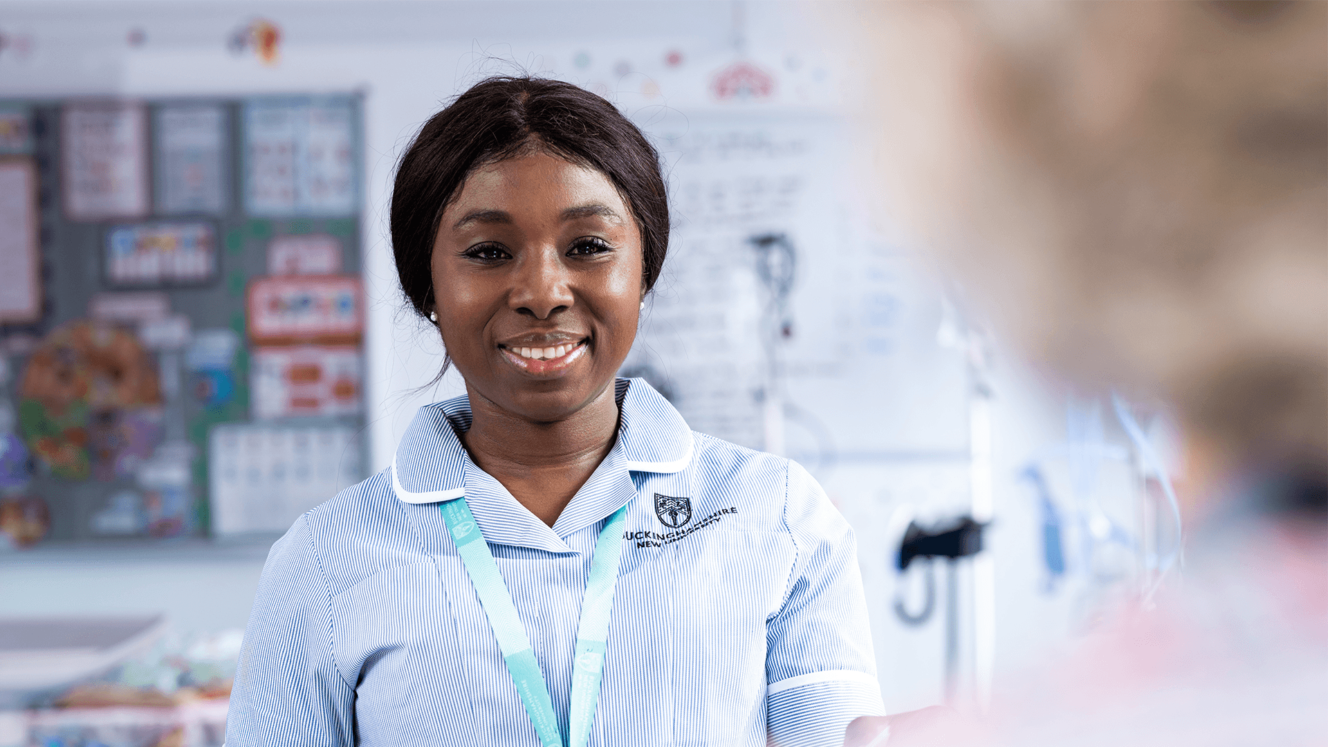 A student nurse in uniform facing the camera and smiling