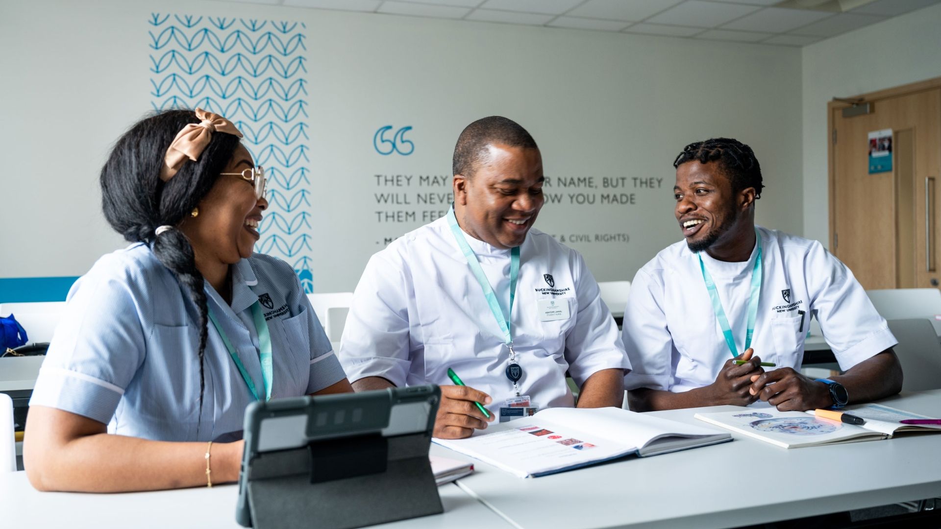 Three nursing students sat at a table next to one another looking at a textbook