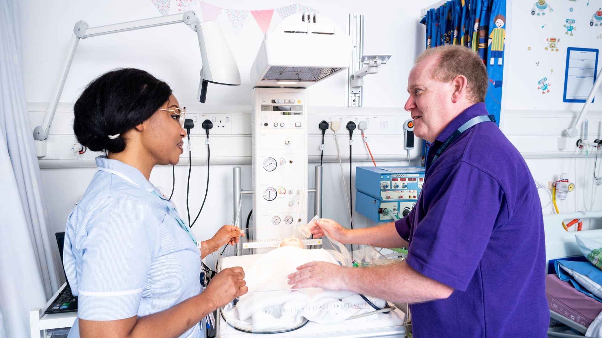 A student nurse stood in a simulation ward next to a lecturer giving words of advice