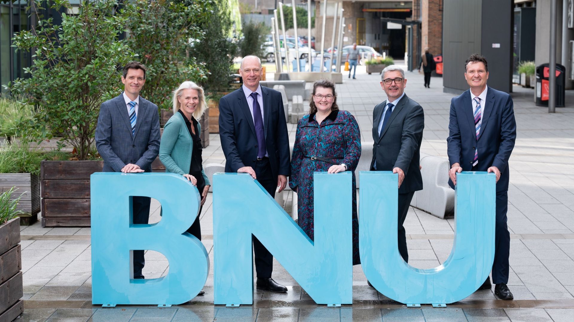 All 6 members of the University Executive Team stood around the BNU letters on the concourse