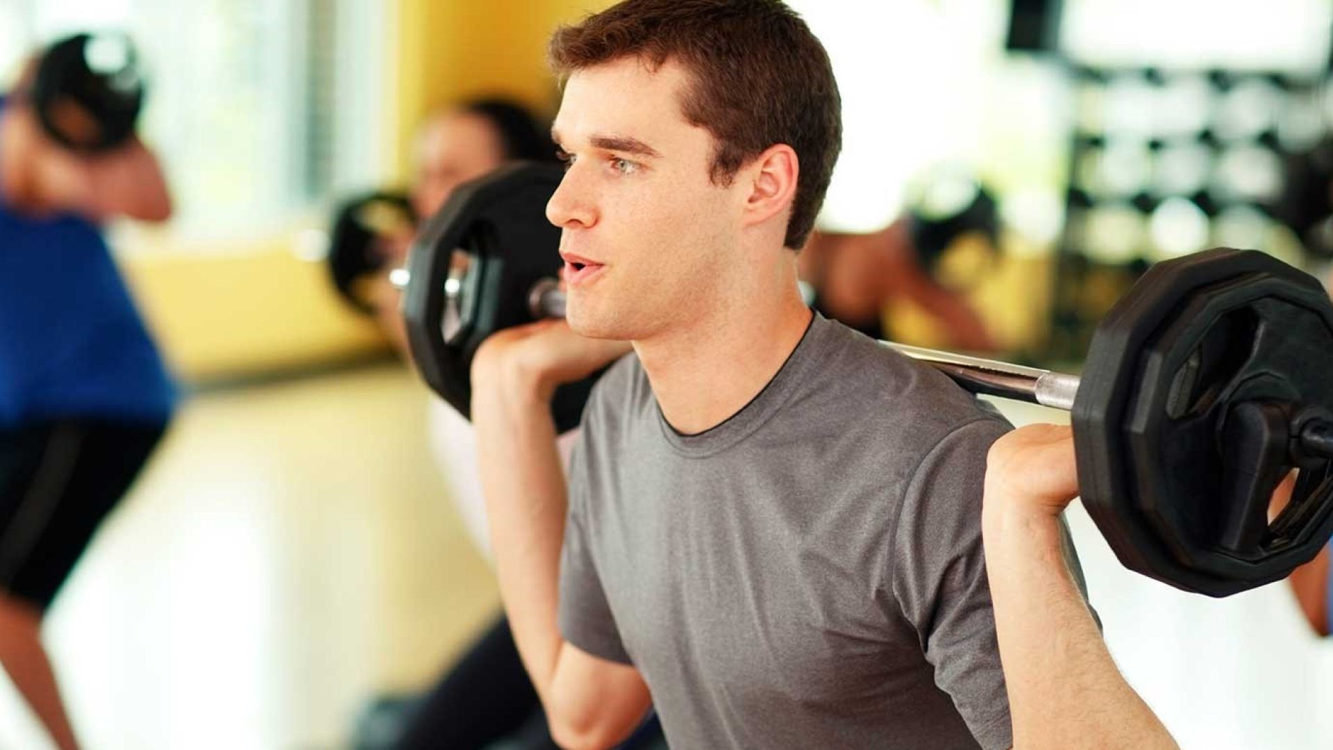 A man squatting with weights on his shoulders in an exercise class