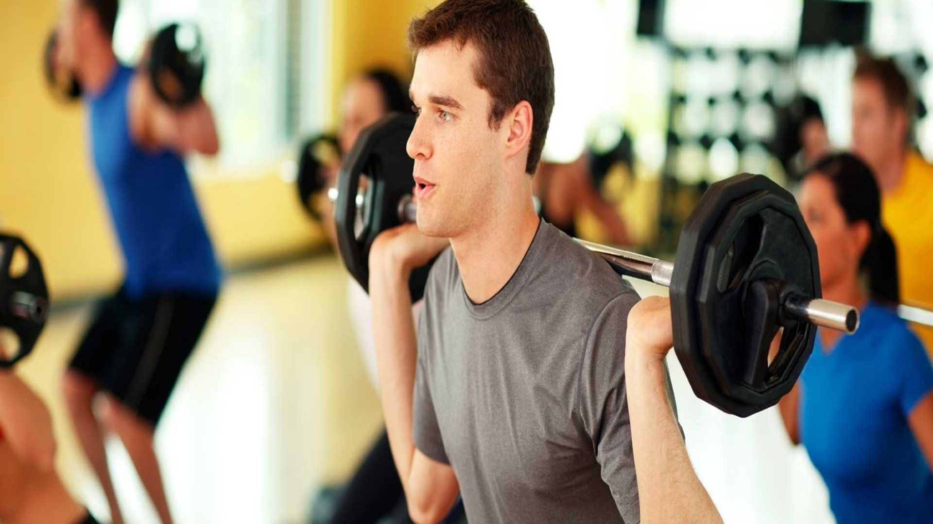 A man squatting with weights on his shoulders in an exercise class