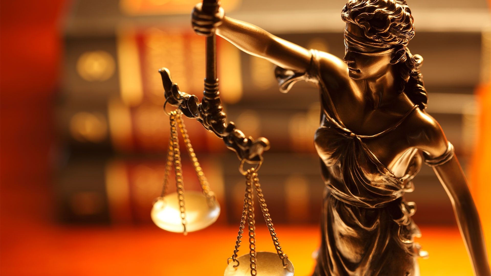 Lady of Justice statue on desk with law books in background