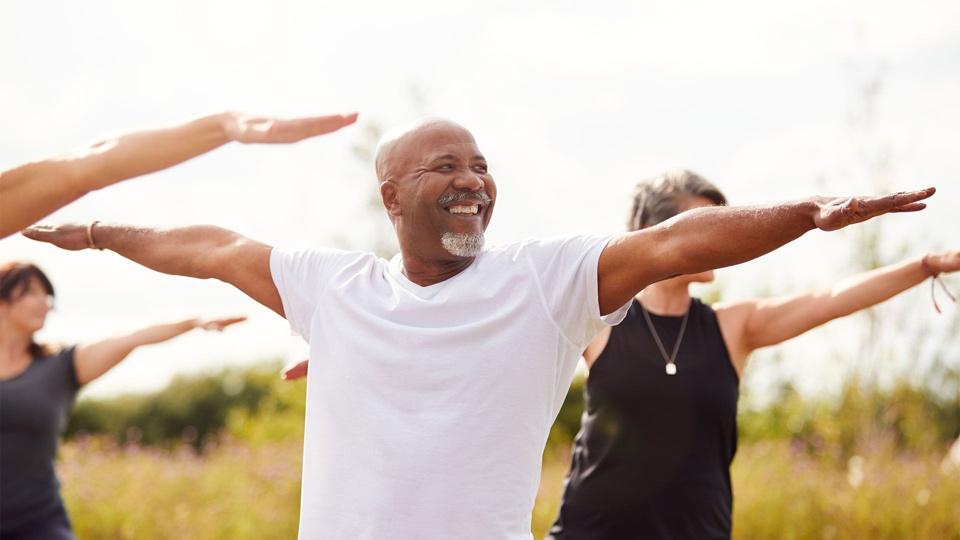 smiling people in a meadow holding yoga poses