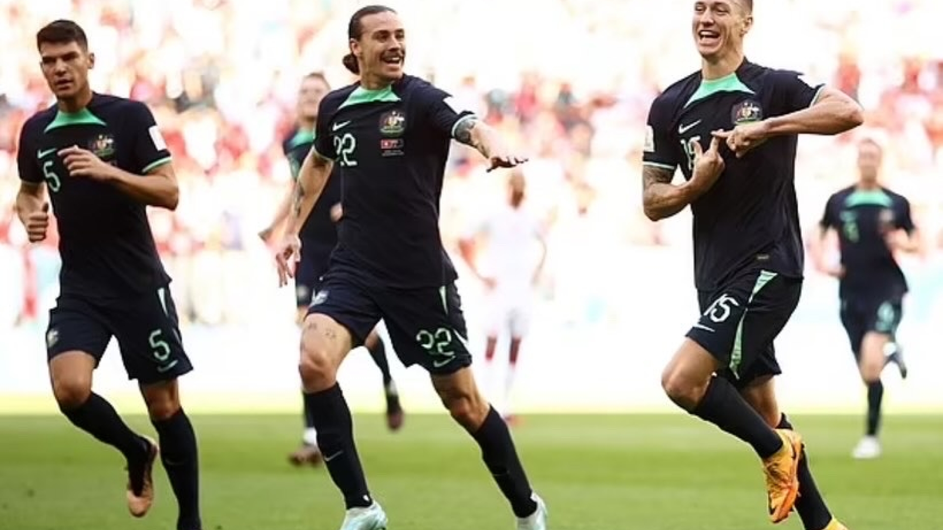 three footballers mid-run on pitch