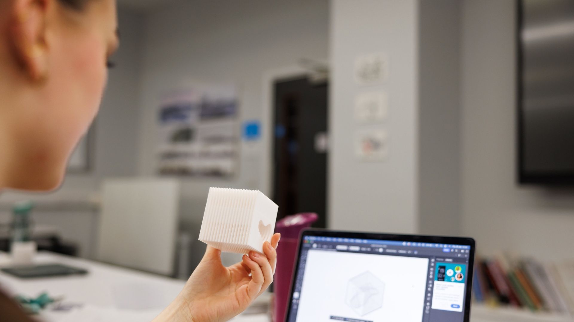 Interior and Spatial student holding a model while looking at a laptop