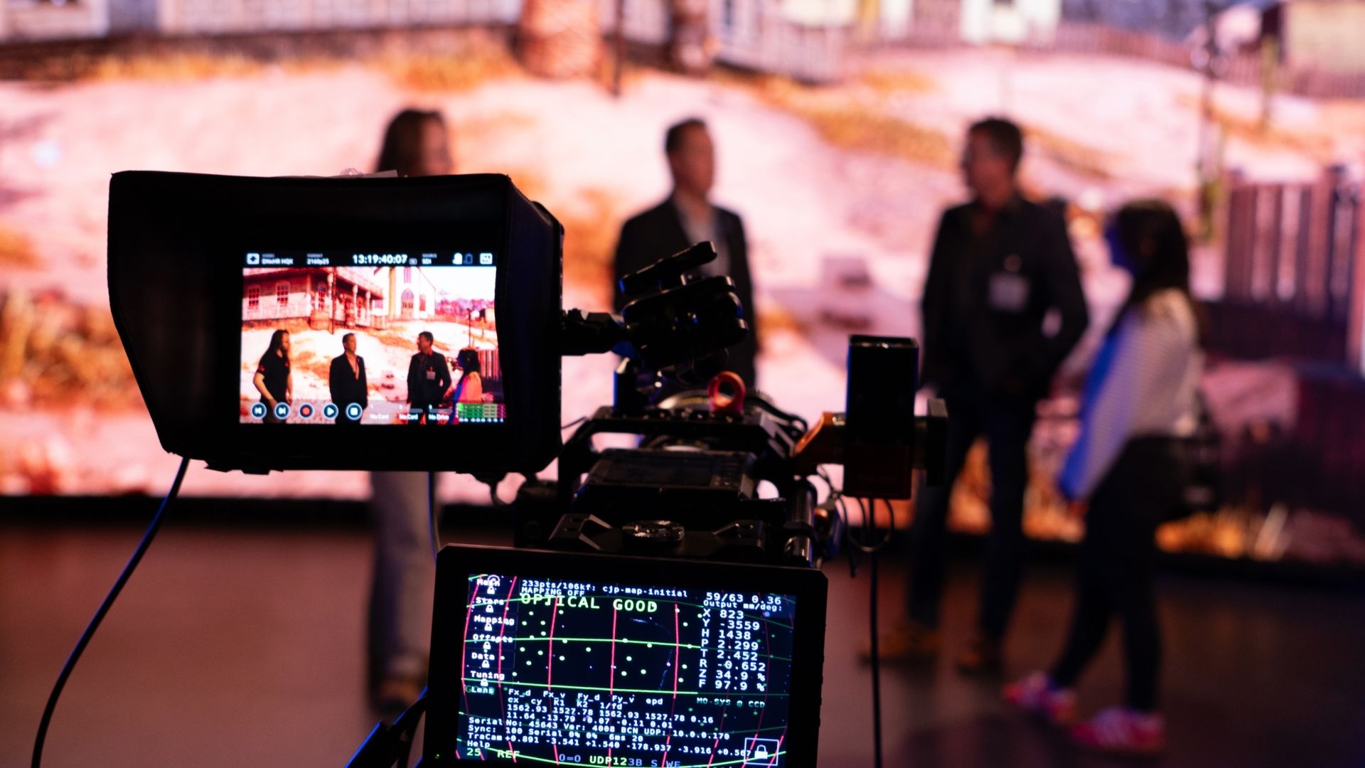 Four people talking in front of an LED Screen, cameras pointing at them