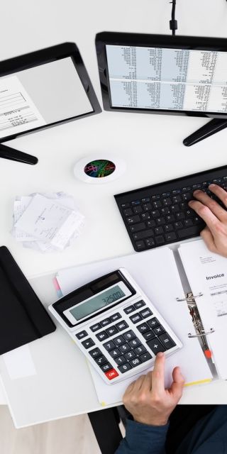 a birds-eye view of a person typing on a key board whilst looking at two screens