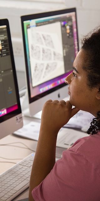two female students sat looking at an Apple Mac computer