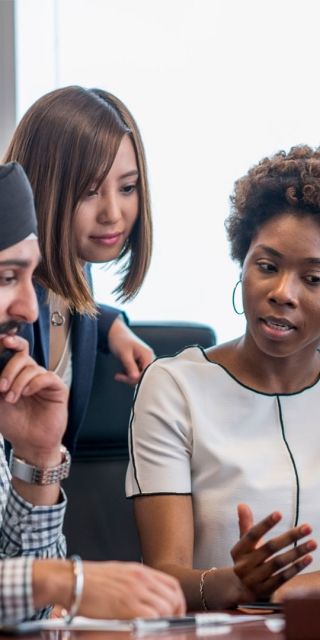 Diverse group of people sat looking at a laptop