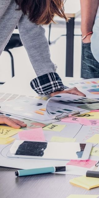 4 staff leaning over a table and looking at various bits of paper and notes
