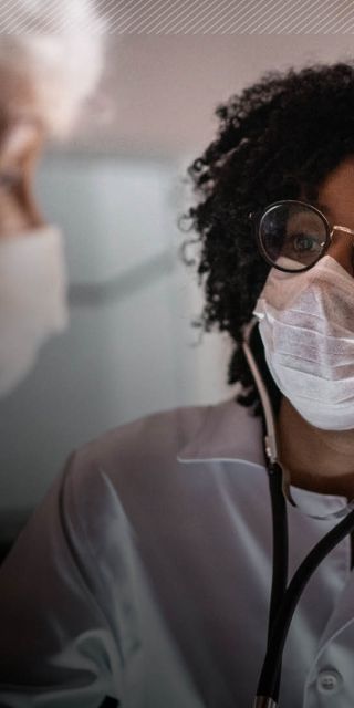 A nurse with a mask and glasses on attends to a patient