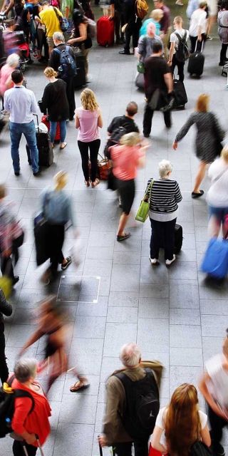People at airport with luggage walking round and looking up 