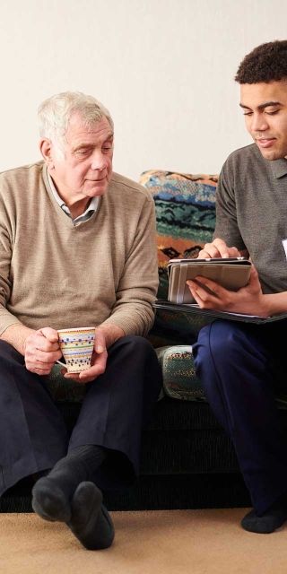 Senior man with crutch sitting with young male care worker