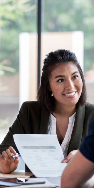 two adults together looking at documents next to a window
