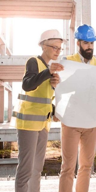Three people looking at a bit of paper on a construction site wearing high vis tops and hard hats