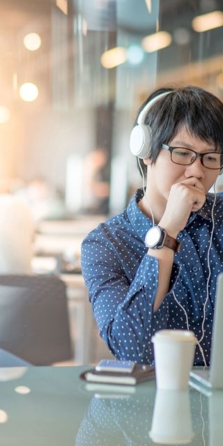 Male student in study room in library with headphones on