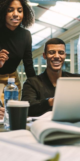 Students together at a table looking at a laptop doing group work