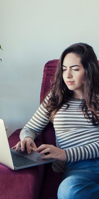 student sat on a sofa using a laptop