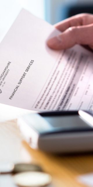 hands using a calculator and holding a BNU financial support document