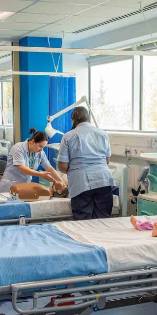 Nursing students in a hospital simulate suite attending to dummies