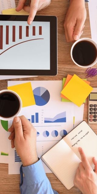 Data presented on bits of paper on a table with 3 people assessing the data in a business meeting
