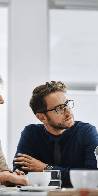 Five members of staff sat around a table talking to one another looking at one another