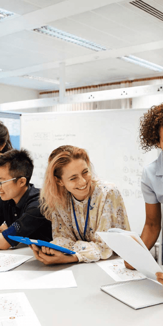 Staff and students discussing student work with one another whilst sat around a table