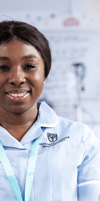 A student nurse in uniform facing the camera and smiling