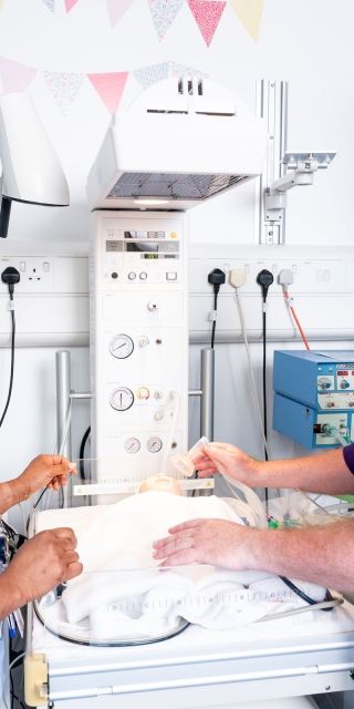 A student nurse stood in a simulation ward next to a lecturer giving words of advice