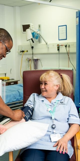 A student nurse testing the blood pressure of another student in a simulation ward