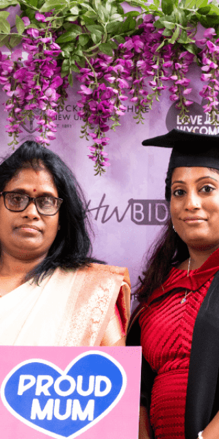 A mum stood with her daughter under some flowers on graduation day