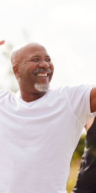smiling people in a meadow holding yoga poses